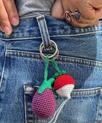 a person's jeans pocket holds a crocheted strawberry keychain