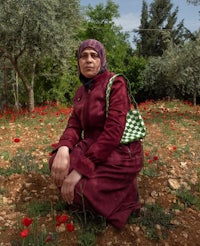 a woman kneeling in a field of red poppies